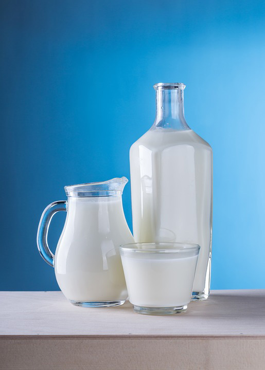 A bottle a jug and a glass of milk placed on the table