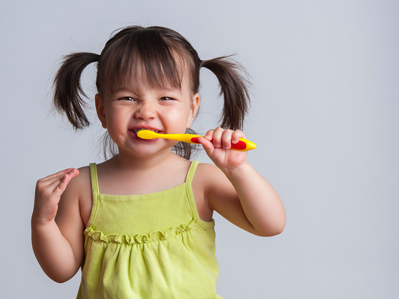 A kid brushing her teeth