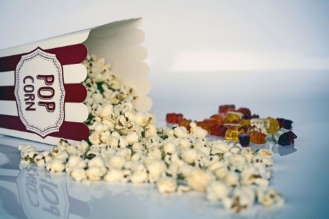 A close-up of popcorn and colorful gummy bears arranged on a clean white surface