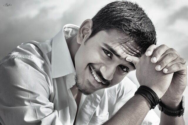 A cheerful man in a white shirt displays a bright smile