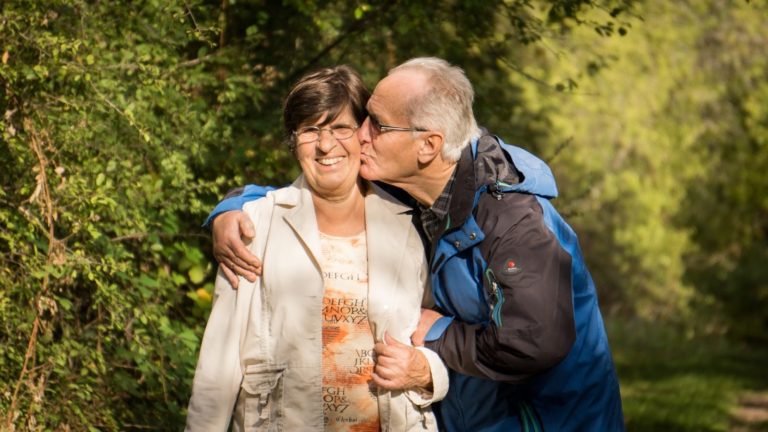 an elderly couple embraces in a loving kiss